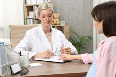 Photo of Doctor consulting pregnant patient at table in clinic