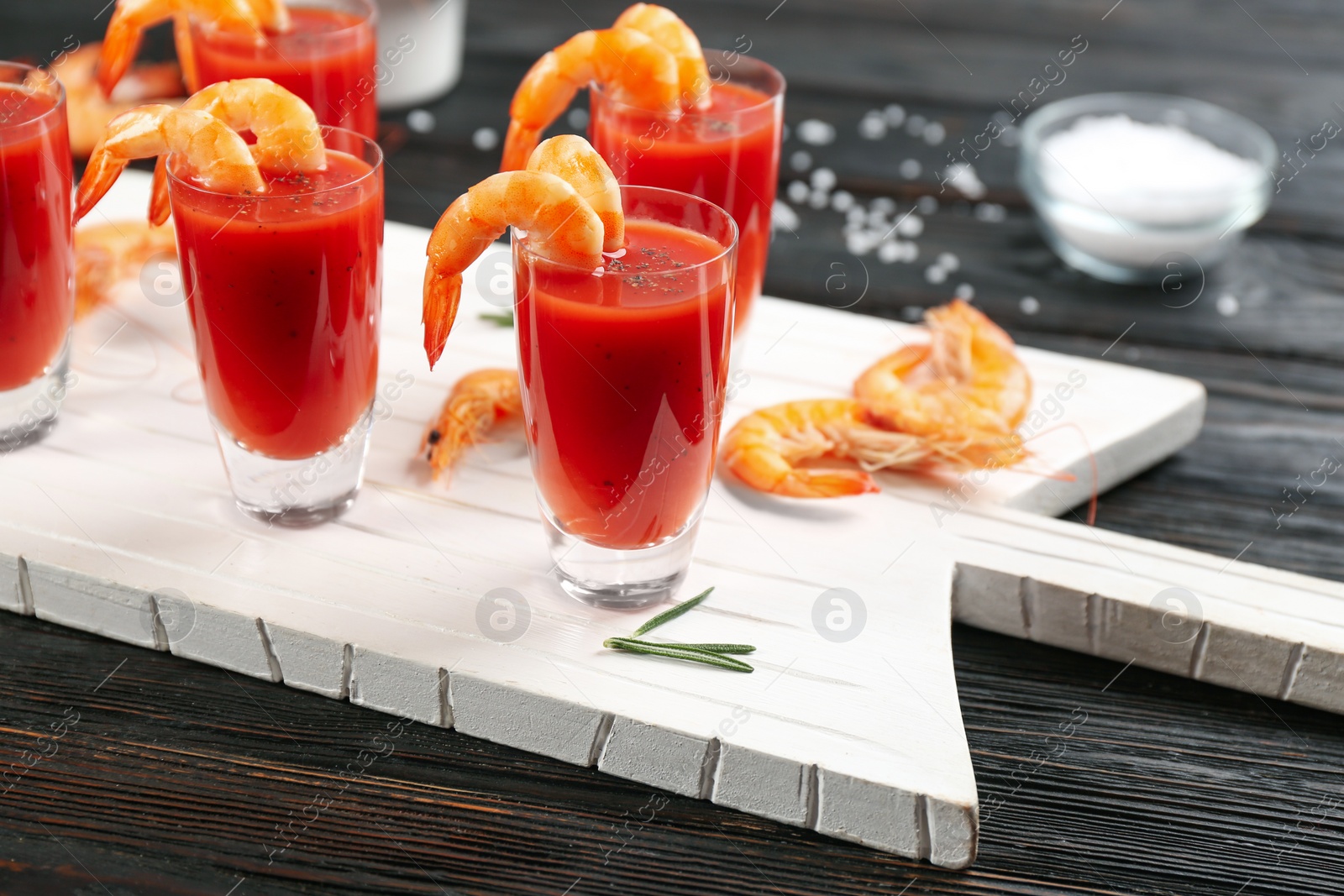 Photo of Delicious shrimp cocktail with tomato sauce served on black wooden table