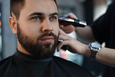 Photo of Professional hairdresser working with client in barbershop, closeup