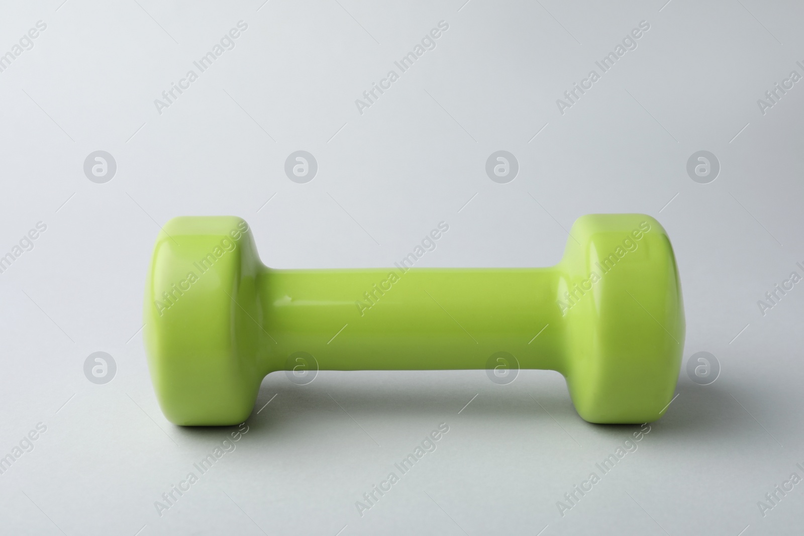 Photo of One new green vinyl dumbbell on light background