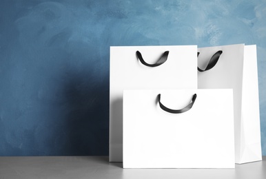 Photo of Paper shopping bags on table against color background. Mock up for design