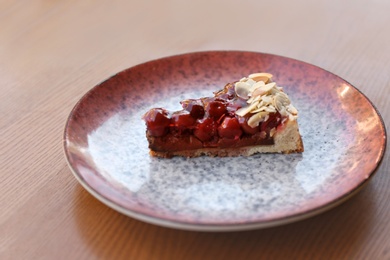 Photo of Plate with slice of cherry cake on wooden table