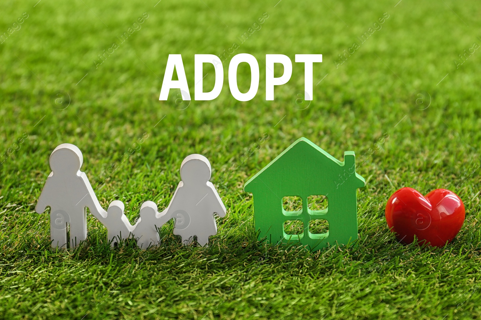 Image of Figures of family, red heart and house on green grass. Child adoption concept