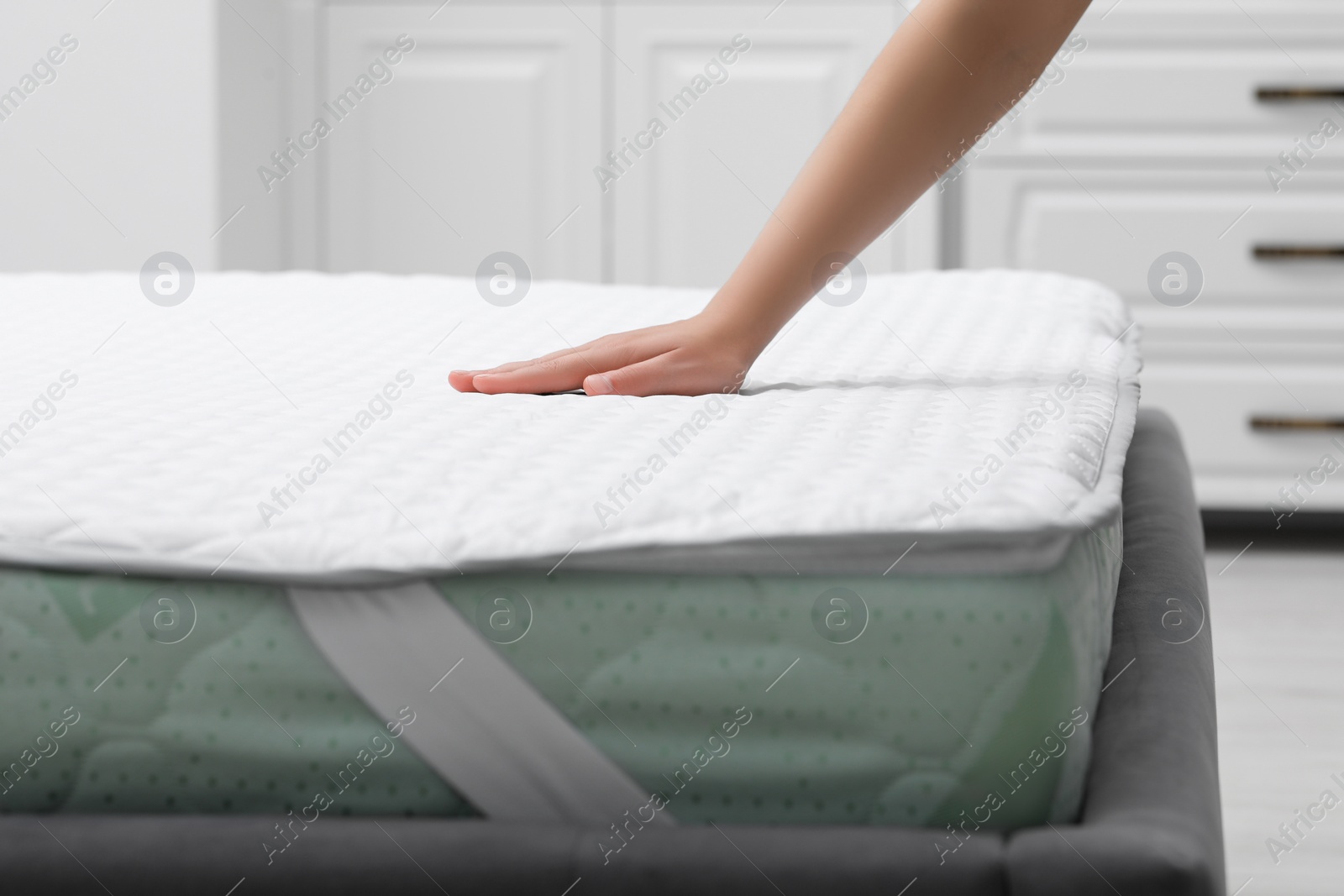 Photo of Woman touching new soft mattress in bedroom, closeup