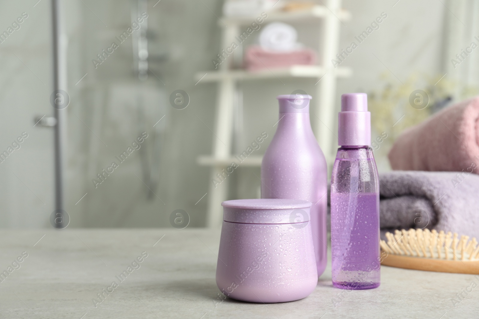 Photo of Set of hair care cosmetic products on light grey stone table in bathroom. Space for text