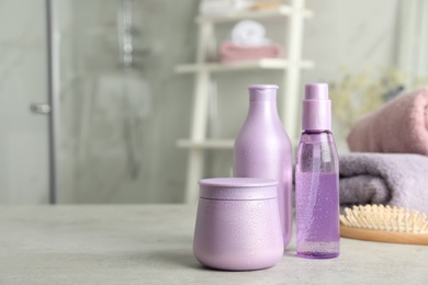 Photo of Set of hair care cosmetic products on light grey stone table in bathroom. Space for text