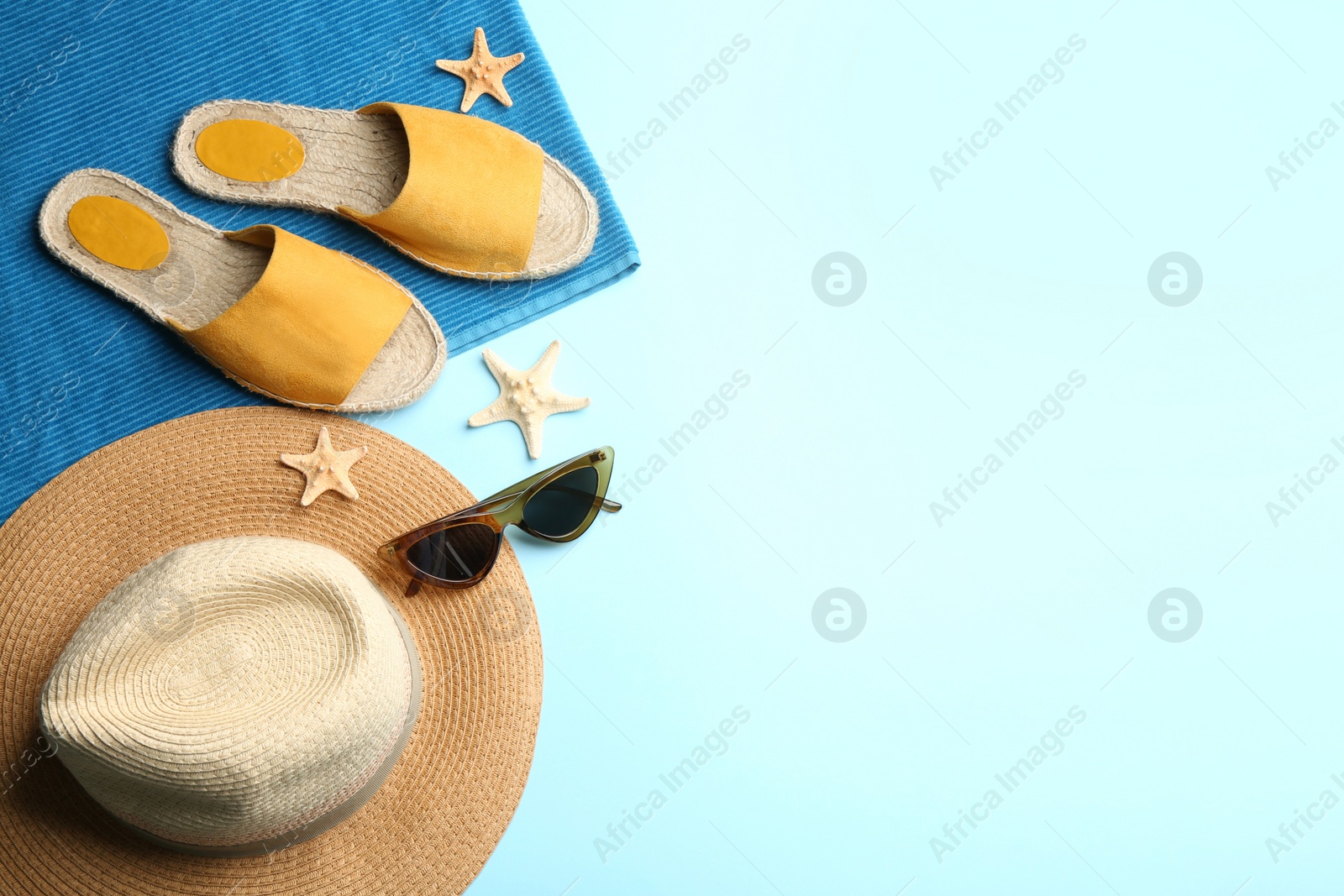 Photo of Beach accessories on light blue background, flat lay. Space for text