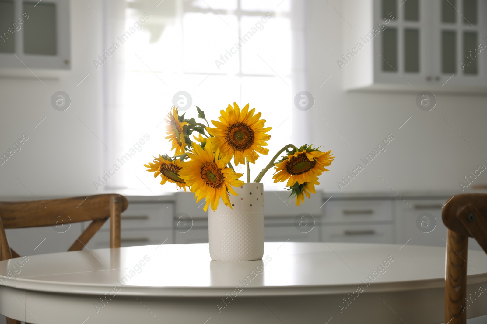 Photo of Bouquet of beautiful sunflowers on table in kitchen