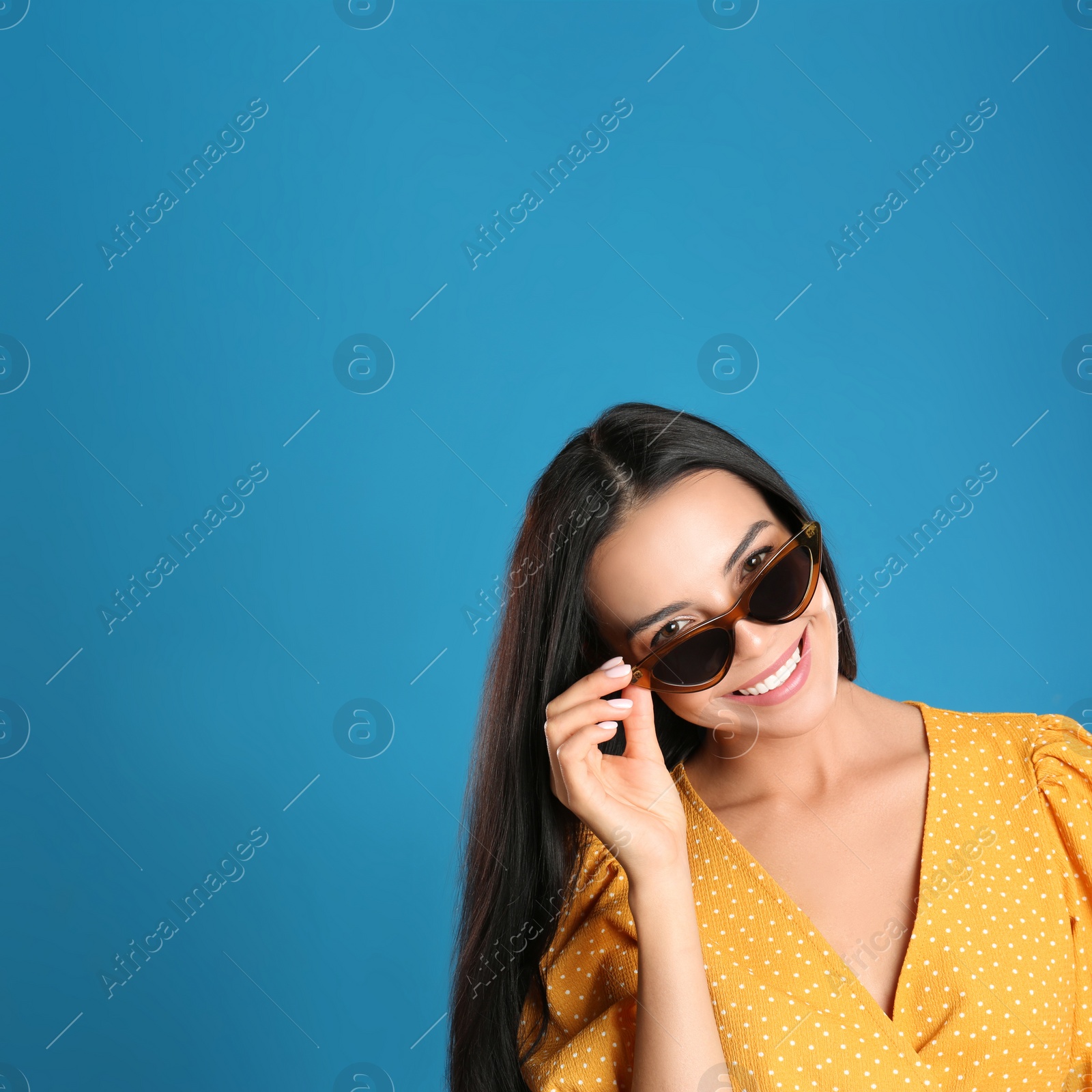 Photo of Beautiful woman wearing sunglasses on blue background. Space for text