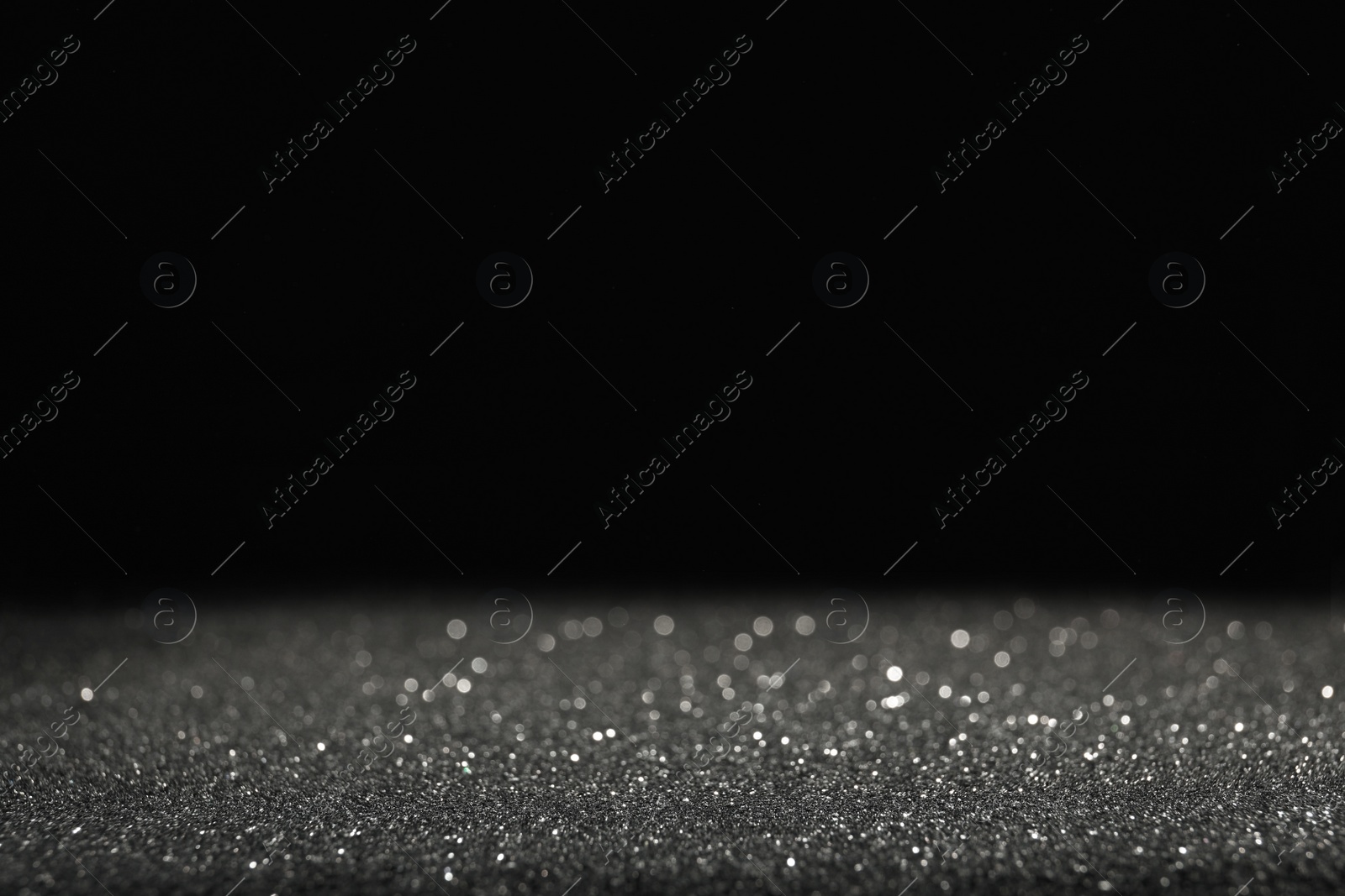 Photo of Shiny grey glitter on black background, space for text. Bokeh effect