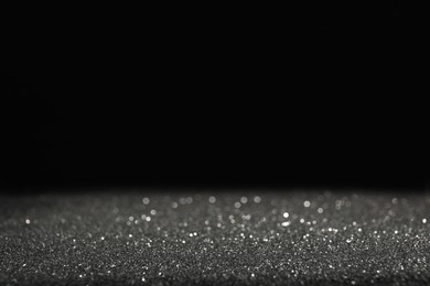 Photo of Shiny grey glitter on black background, space for text. Bokeh effect