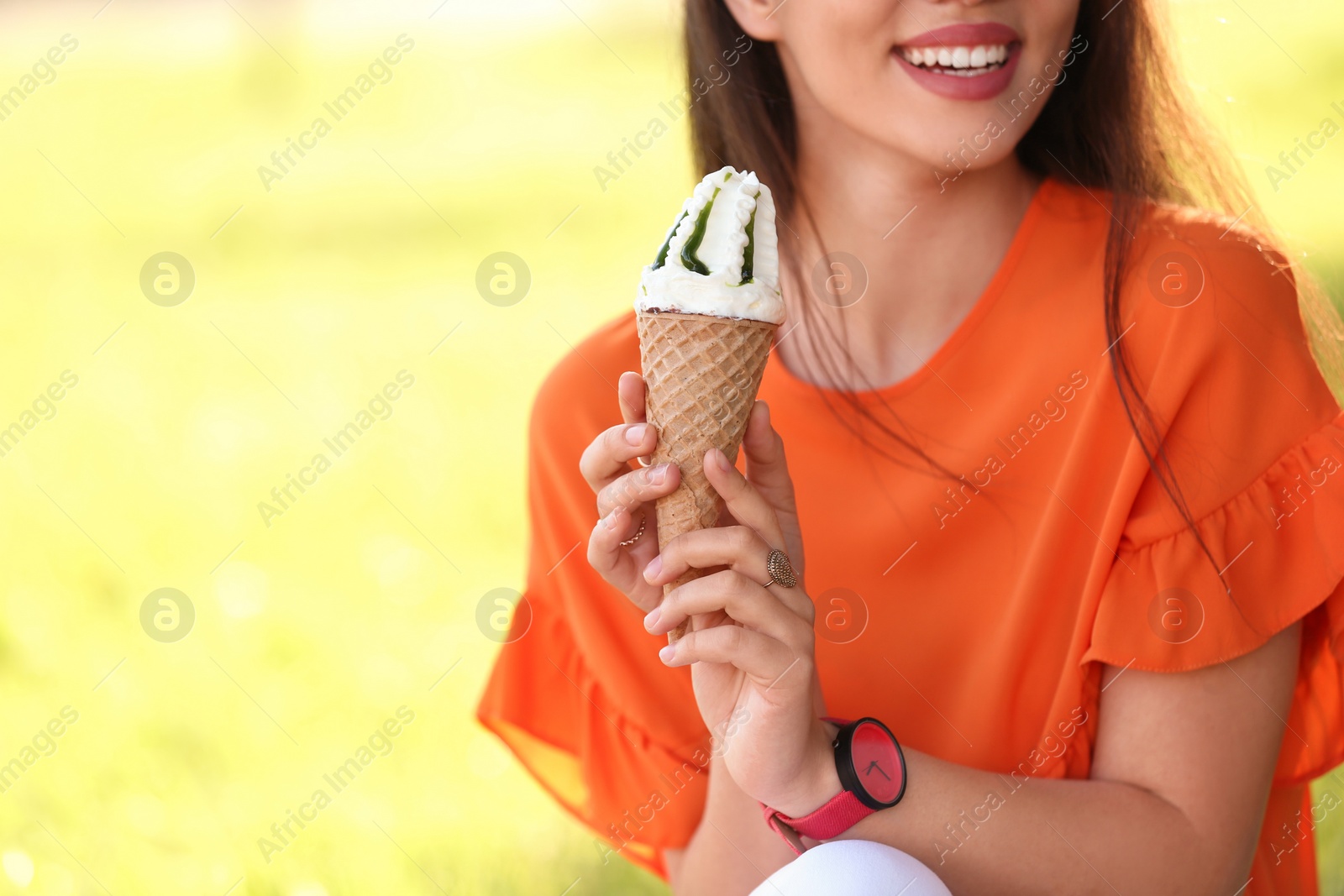 Photo of Happy young woman with delicious ice cream in waffle cone outdoors, closeup. Space for text