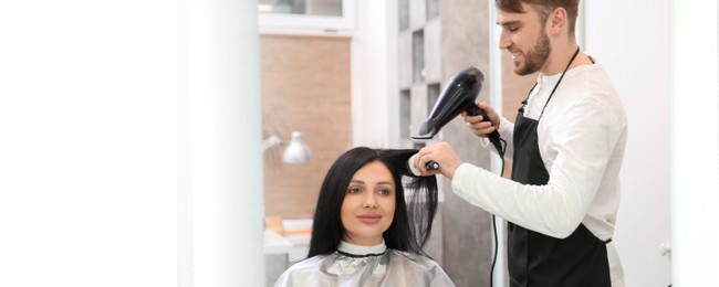 Image of Professional male hairdresser working with client in salon. Banner design