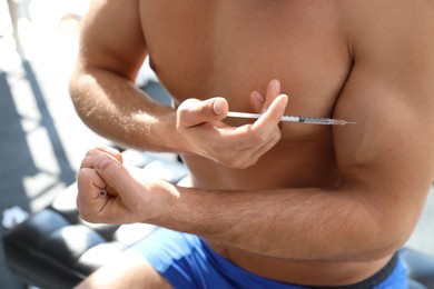 Photo of Athletic man injecting himself indoors, closeup. Doping concept