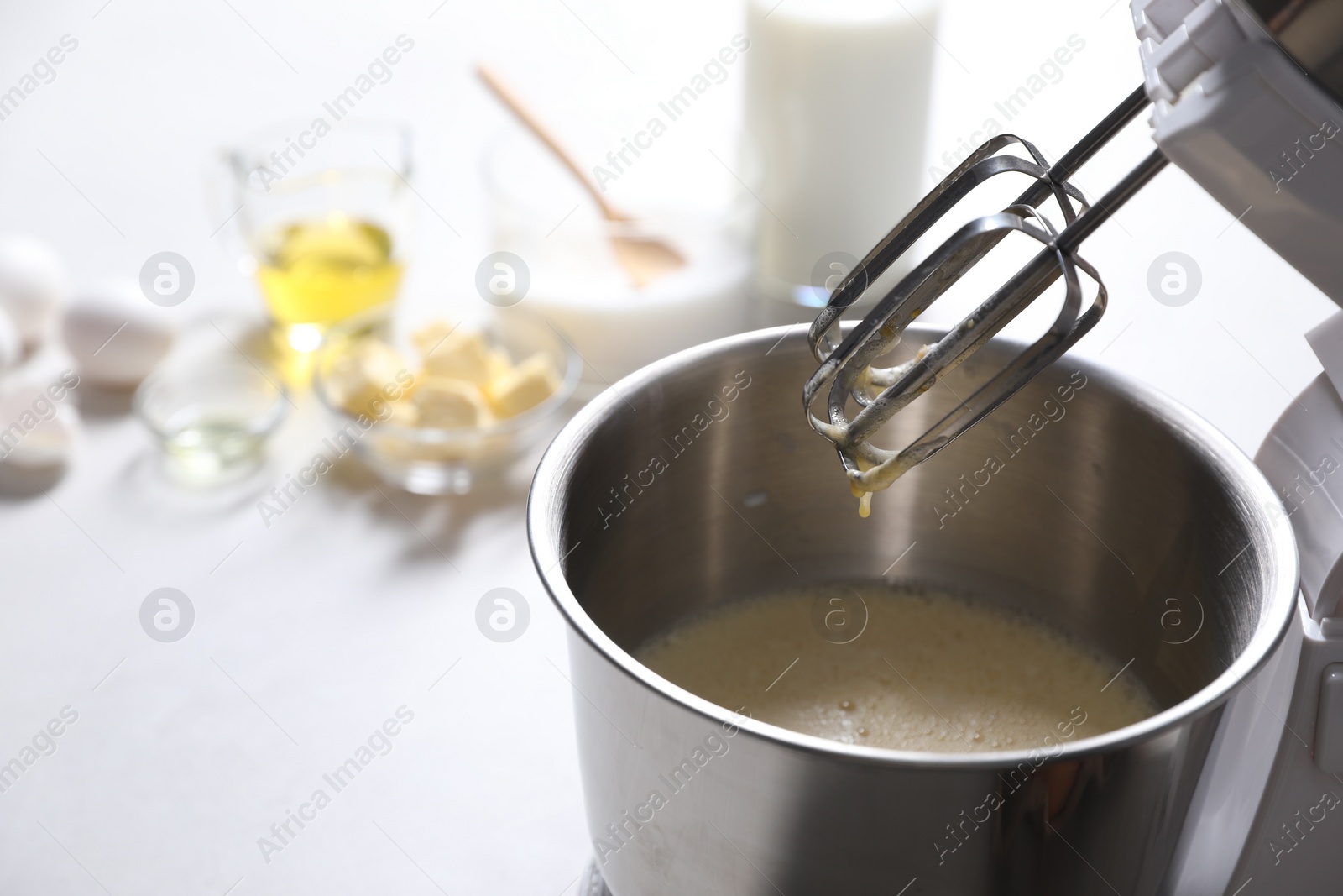 Photo of Making dough in bowl of stand mixer on white table. Space for text