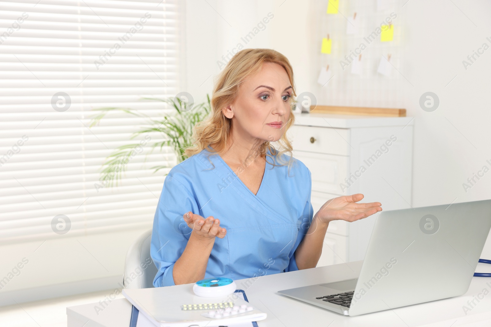 Photo of Doctor with laptop consulting patient in clinic. Online medicine concept