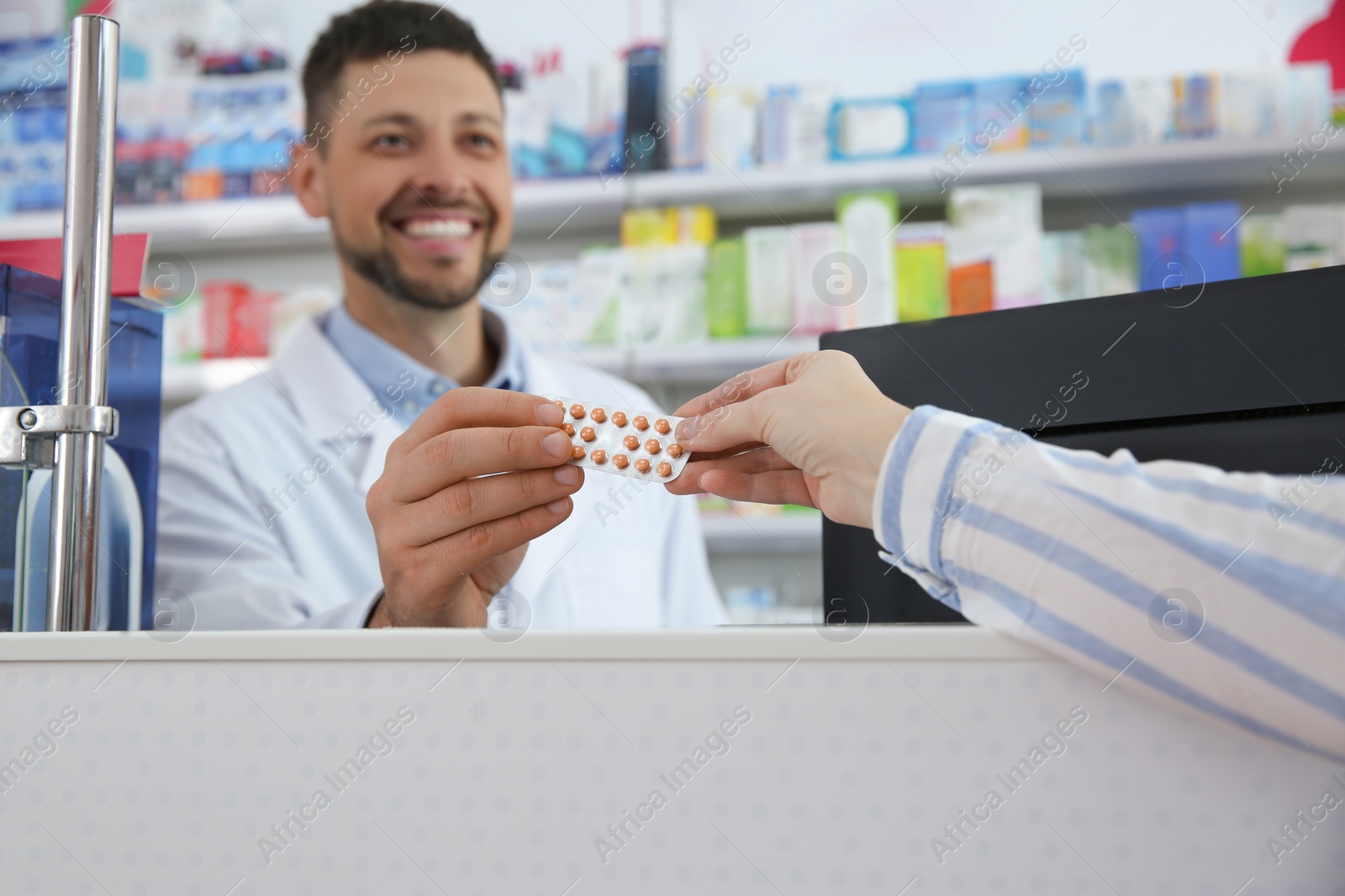 Photo of Professional pharmacist giving pills to customer in drugstore
