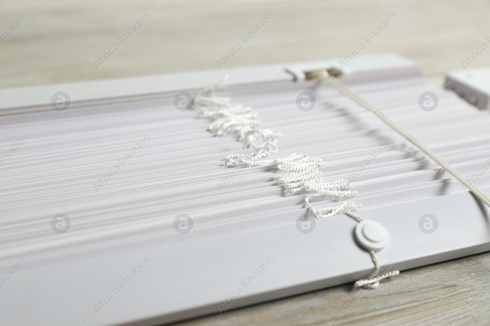 Photo of Stylish horizontal window blinds on wooden table, closeup