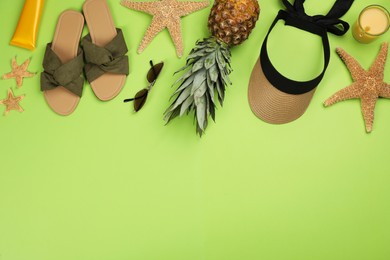 Flat lay composition with beach objects on green background, space for text