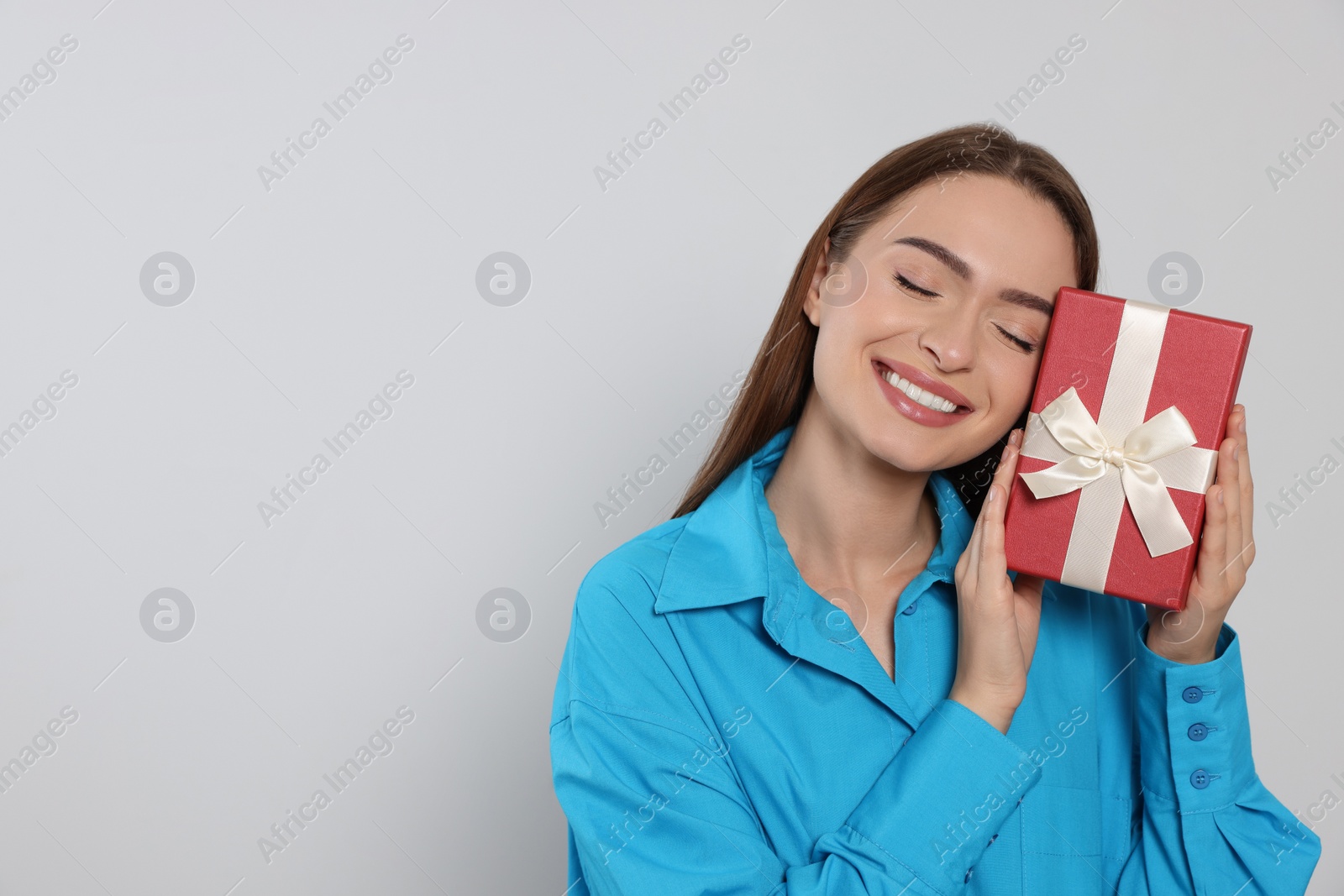 Photo of Portrait of happy young woman with gift box on grey background. Space for text