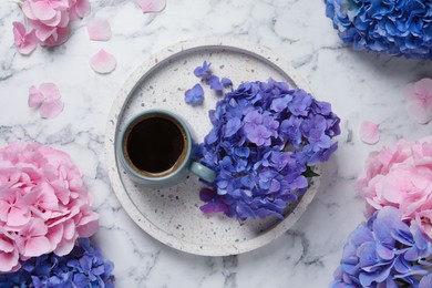 Photo of Beautiful hortensia flowers and coffee on white marble table, flat lay