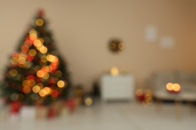 Blurred view of beautiful Christmas tree decorated with festive lights in stylish room. Interior design