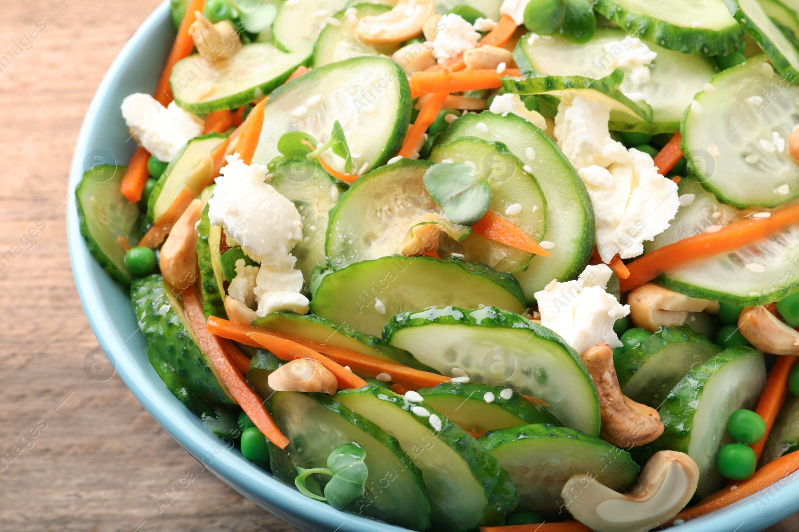 Photo of Delicious cucumber salad on wooden table, closeup