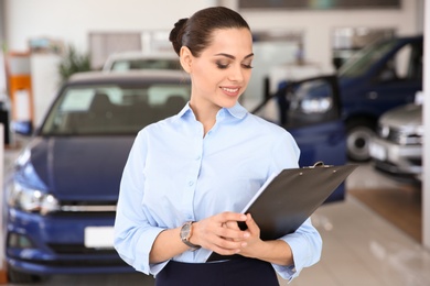 Photo of Portrait of young saleswoman in car dealership