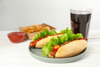 Photo of Tasty hot dogs and refreshing drink served on white wooden table, closeup. Fast food