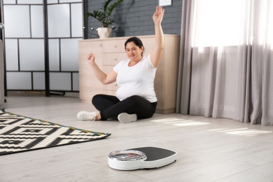 Photo of Scales and happy overweight woman on background