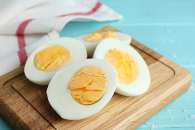 Photo of Cut hard boiled chicken eggs on wooden board