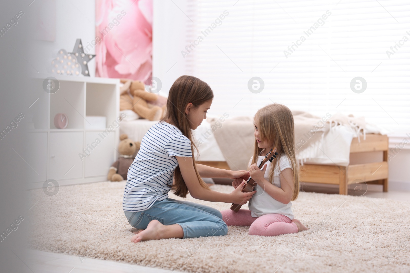 Photo of Cute little sisters spending time together at home