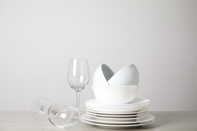 Photo of Clean plates, bowls and glasses on table against white background. Space for text