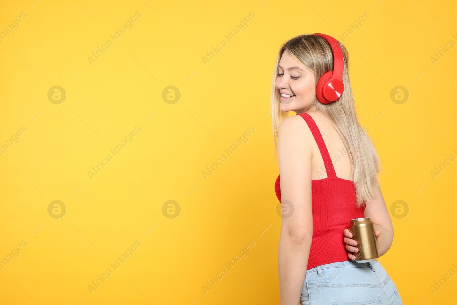 Photo of Beautiful happy woman holding beverage can on yellow background. Space for text