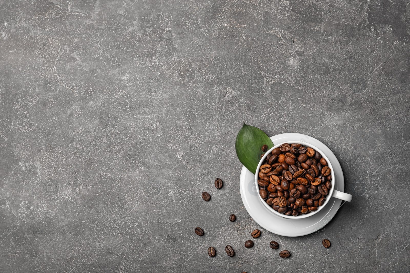 Photo of Cup with roasted coffee beans on grey background