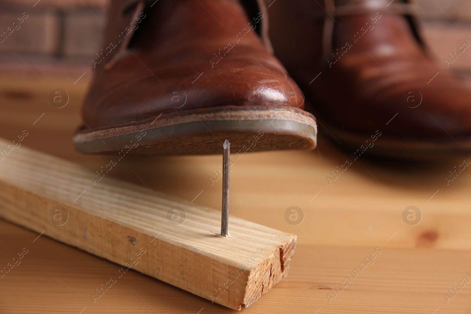 Photo of Metal nail in wooden plank and shoes on table, closeup