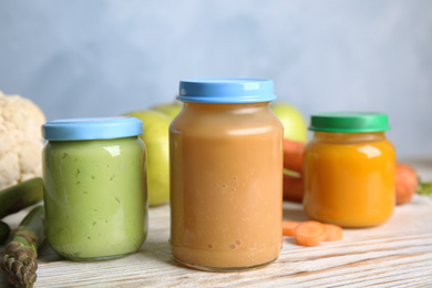 Photo of Jars with baby food and fresh ingredients on white wooden table