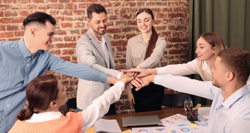 Image of Business partners. Group of people holding hands together in office. Banner design