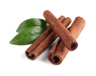 Cinnamon sticks and green leaves isolated on white