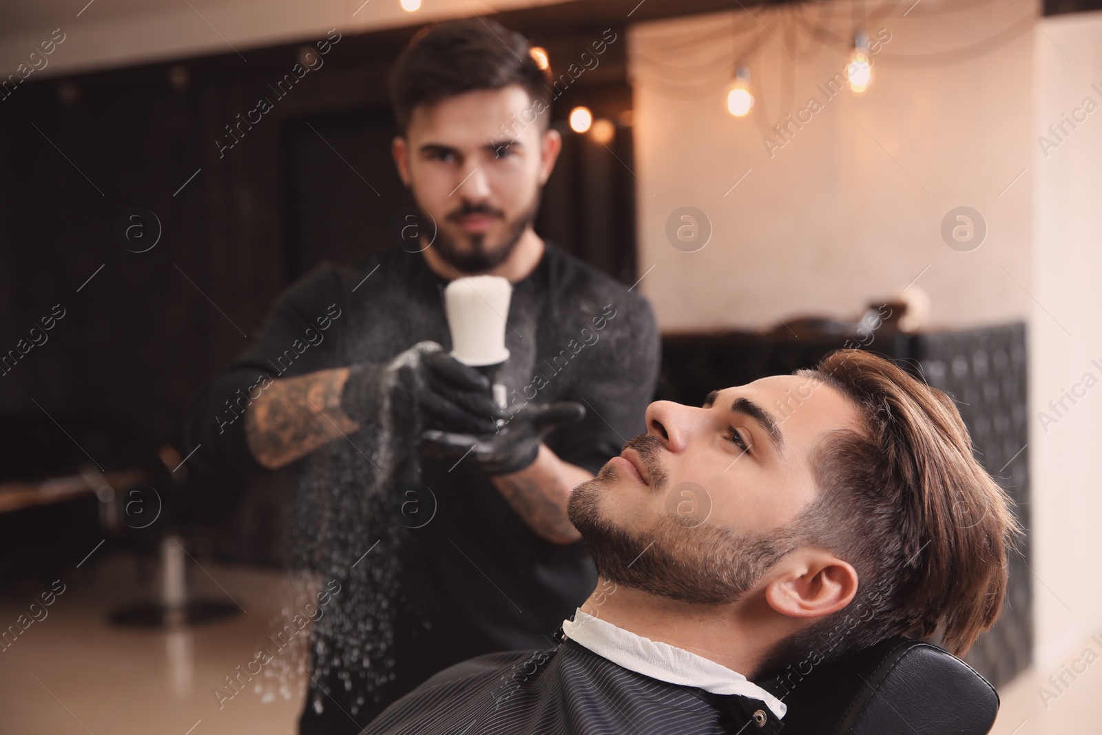 Photo of Young man and hairdresser in barbershop. Professional shaving service