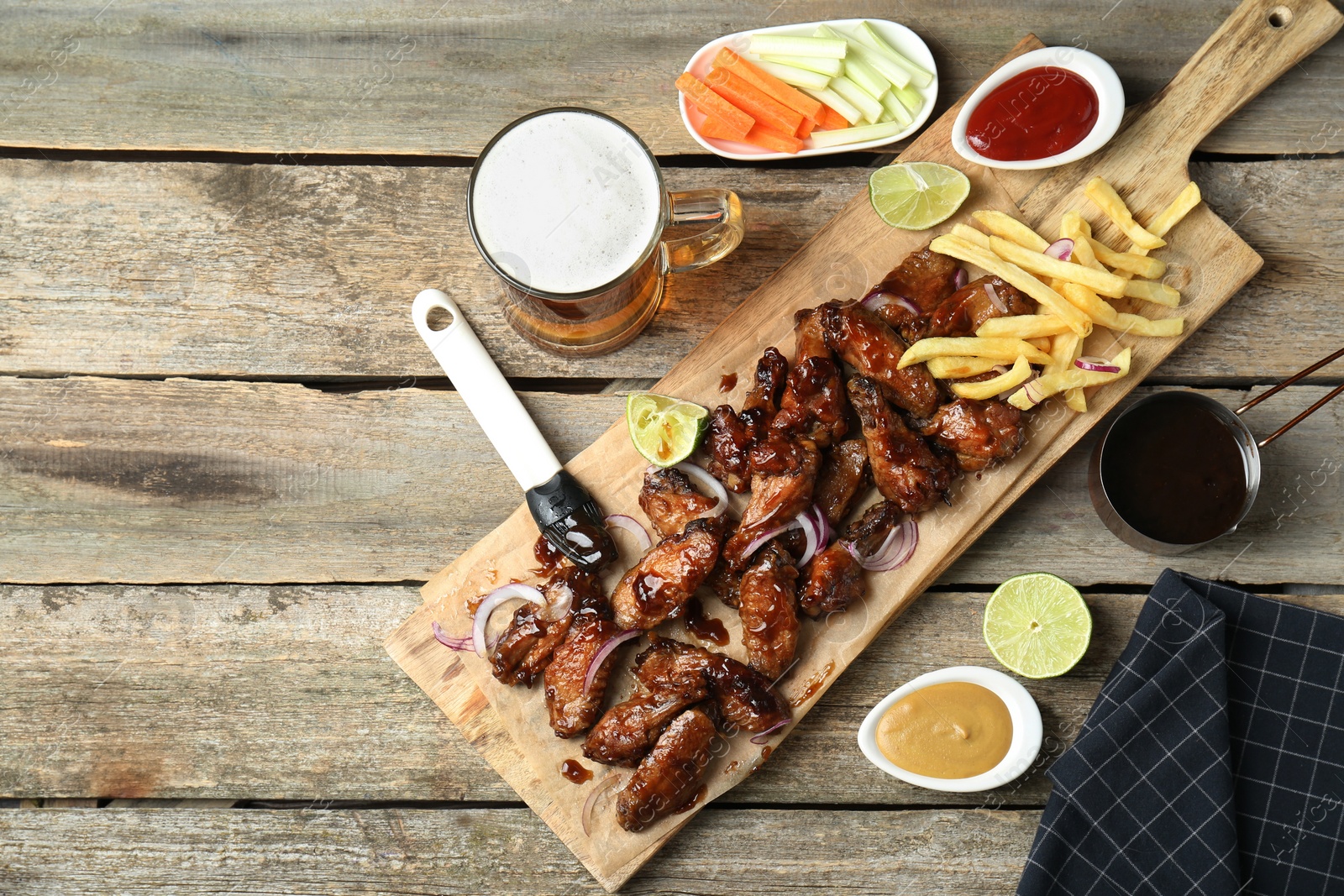 Photo of Tasty roasted chicken wings served with beer on wooden table, flat lay. Space for text