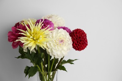 Photo of Bouquet of beautiful Dahlia flowers near white wall, closeup