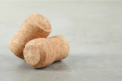 Photo of Corks of wine bottles on light grey table, closeup. Space for text