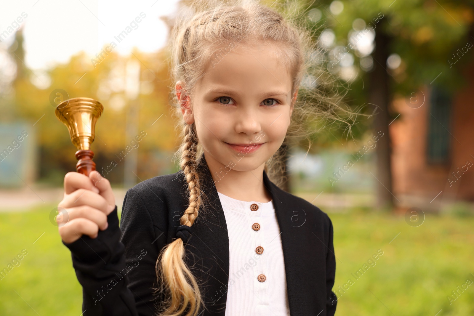 Photo of Pupil with school bell outdoors on sunny day