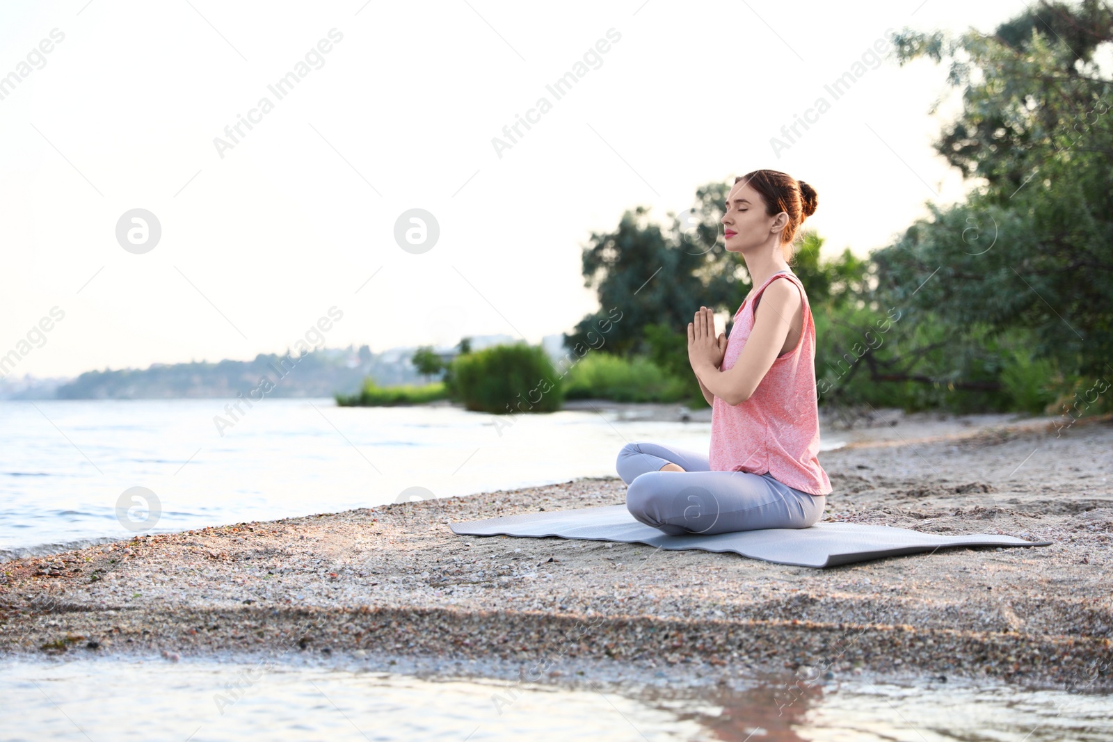 Photo of Young woman practicing yoga on beach. Zen meditation