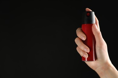 Photo of Woman holding pepper spray on black background, closeup. Space for text
