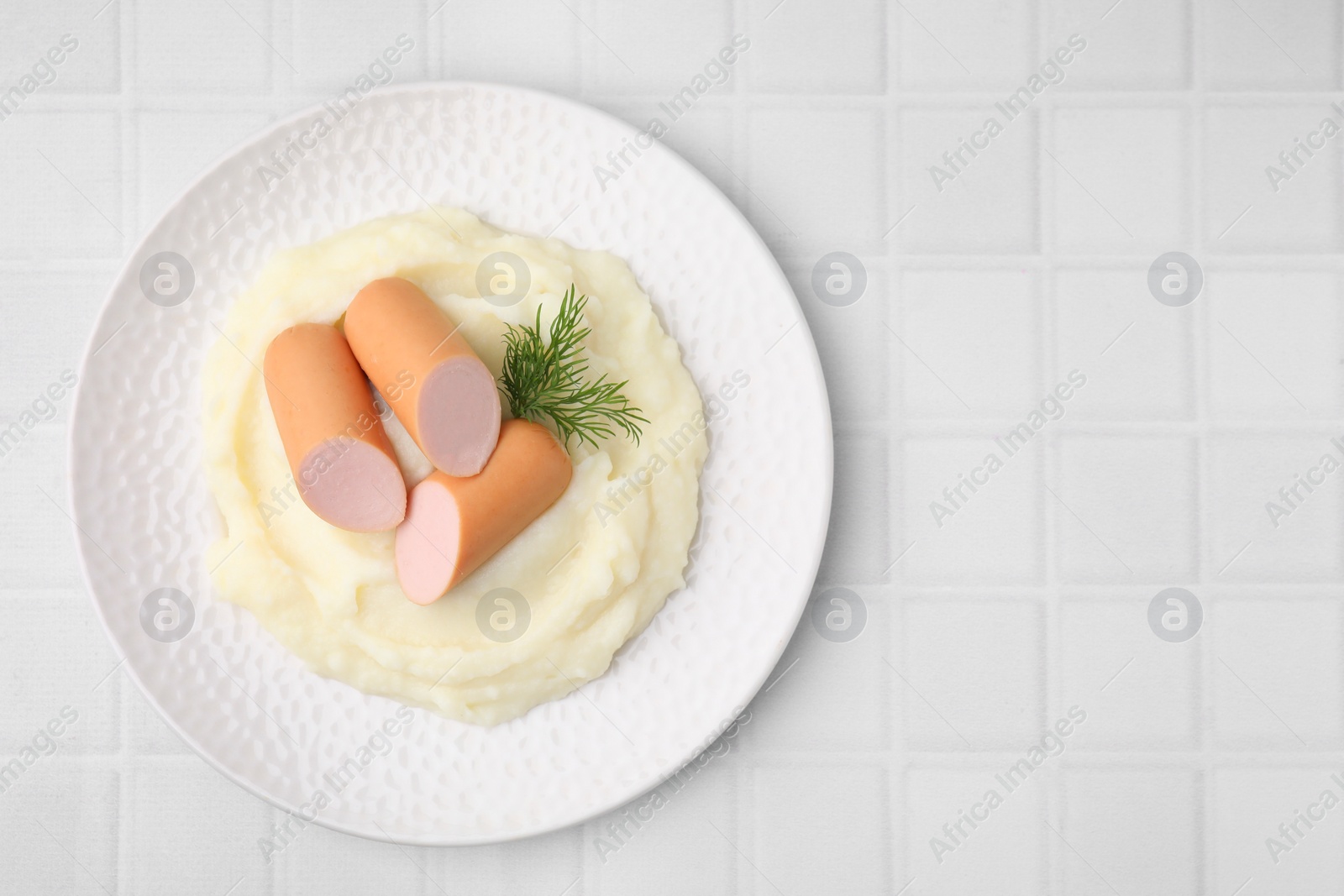 Photo of Delicious boiled sausages, mashed potato and dill on white tiled table, top view. Space for text