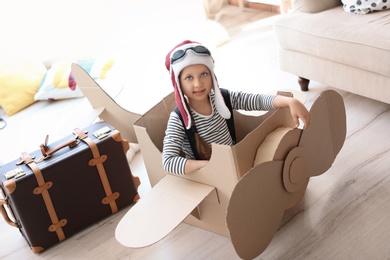 Adorable little child playing with cardboard plane at home