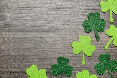 Photo of Decorative clover leaves on grey wooden table, flat lay with space for text. Saint Patrick's Day celebration