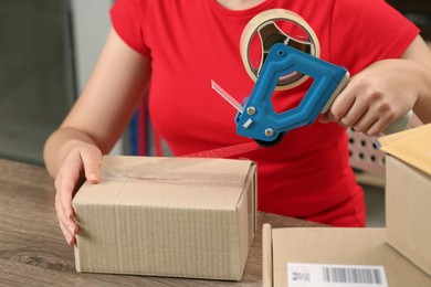 Post office worker packing parcel at counter indoors, closeup